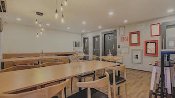 A dining area with wooden tables and chairs, hanging light fixtures, and framed artwork on the walls.