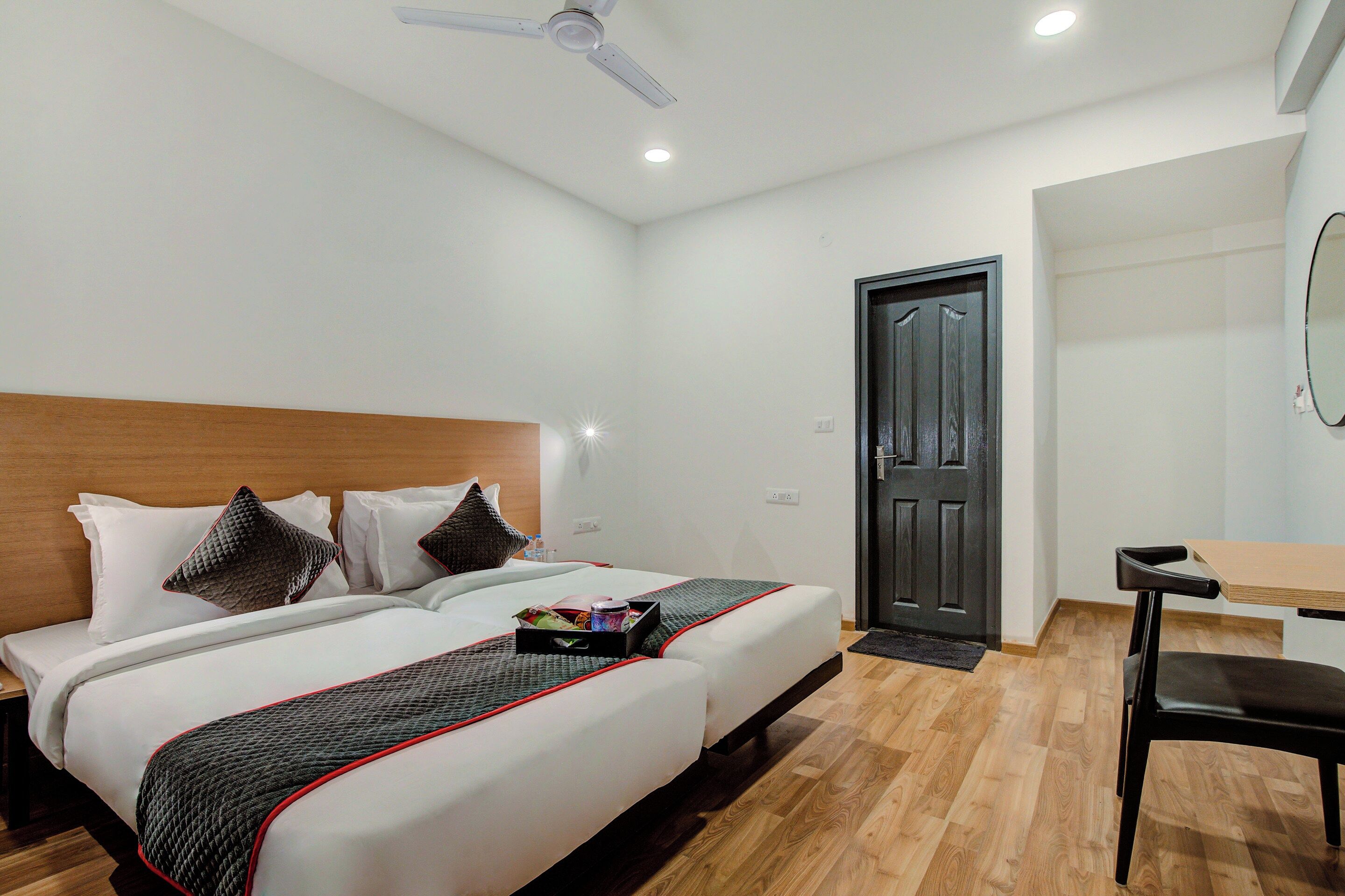 A hotel room with a bed, bedside table, chair, and a door.