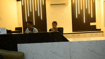 A reception desk with a marble top, a wall-mounted air conditioner, and vertical light fixtures.