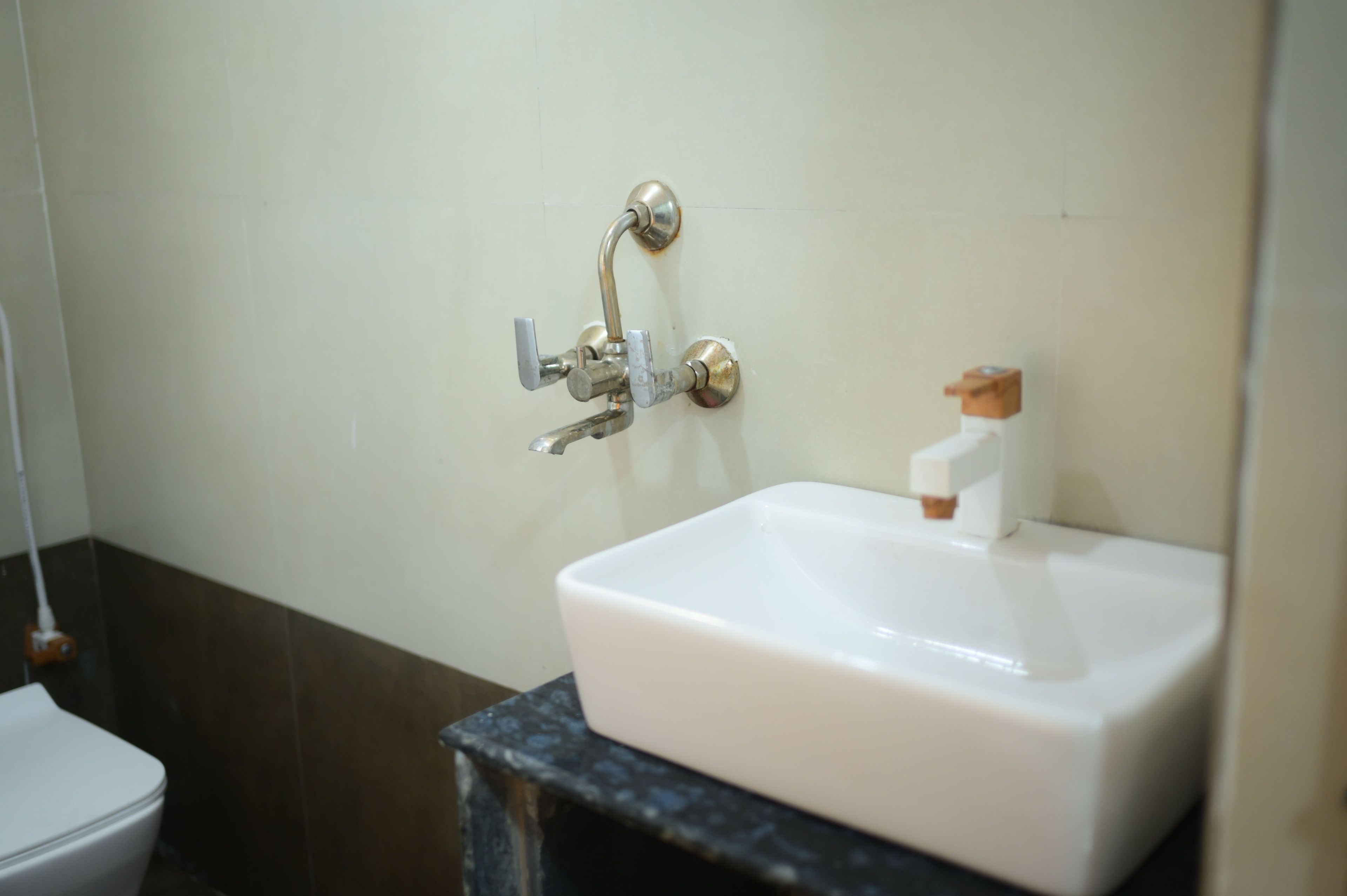 A bathroom with a white sink, a faucet, and a toilet.