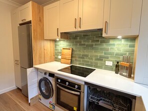 A compact kitchen with a washing machine, oven, and a dishwasher. - Chic Ground Floor 2BDR Apartment in Ashfield (Ashfield)