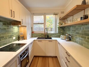 A kitchen with white cabinets, a black sink, a window with a view, and a countertop with a toaster and a kettle. - Chic Ground Floor 2BDR Apartment in Ashfield (Ashfield)