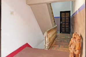Una escalera con barandilla, una puerta con tallado intrincado y una pared con interruptor de luz.