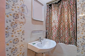 Een badkamer met een witte wastafel, een spiegel en een douchegordijn met een geometrisch patroon.