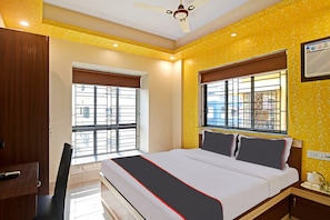 A hotel room with a bed, a desk, a chair, and two windows with metal bars. - Hotel O Comfort N Cozy (Kolkata)