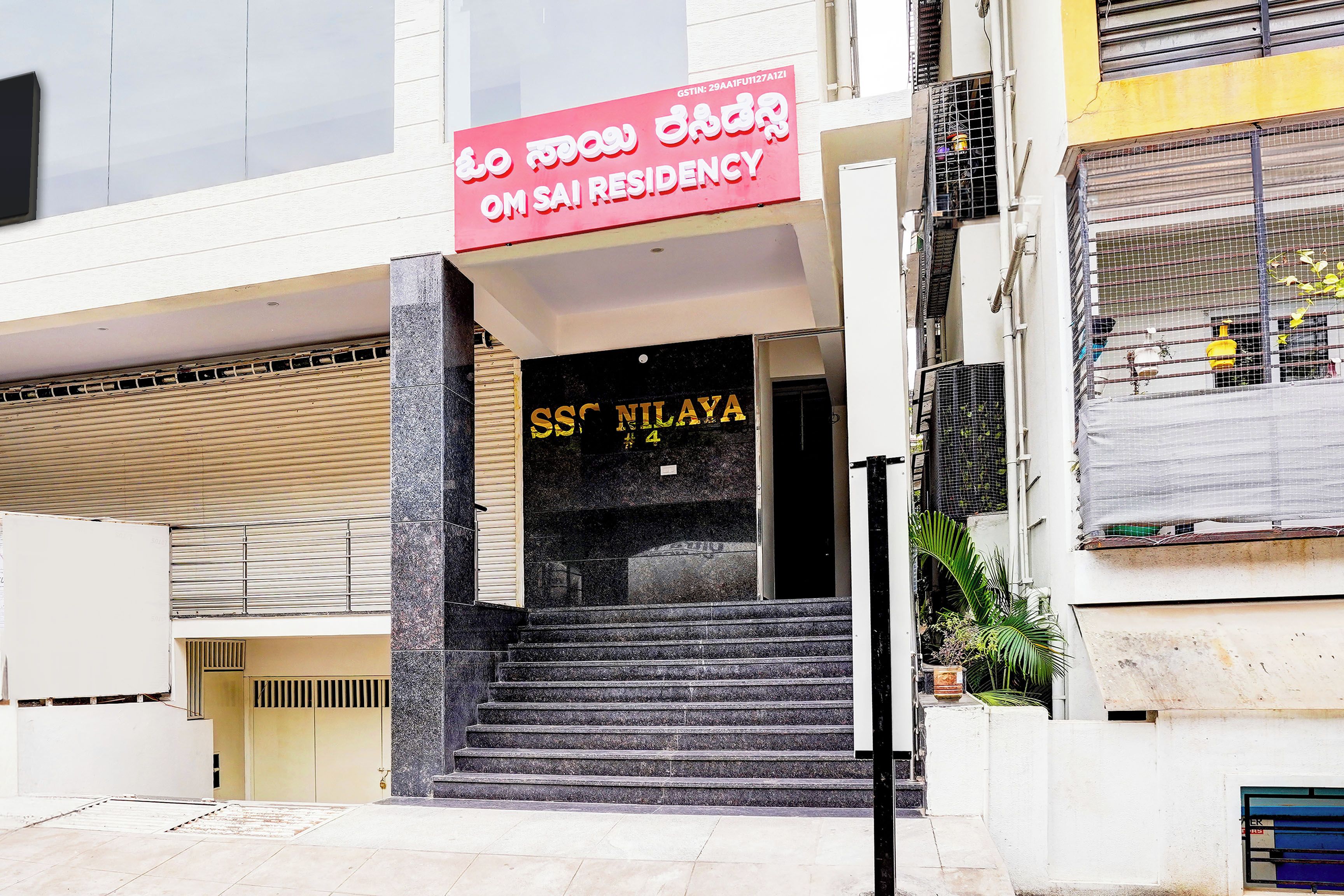 A building entrance with a sign for 'SSNILAYA' and a staircase leading to the entrance.