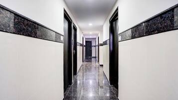 A corridor with a polished floor, white walls, and black doors.