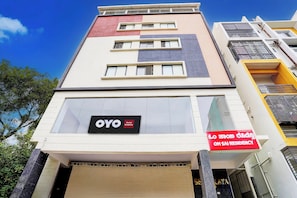 Un edifici de diverses plantes amb una botiga que diu 'OYO Om Sal Residency'.