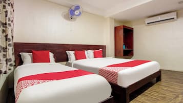 Habitación de hotel con dos camas, ventilador de techo, unidad de aire acondicionado y armario de madera.