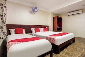 Habitación de hotel con dos camas, ventilador de techo, unidad de aire acondicionado y armario de madera.
