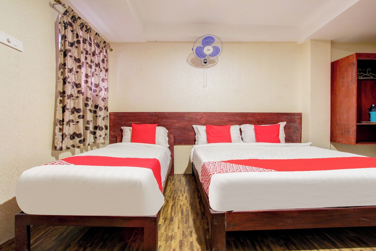 Habitación de hotel con dos camas, cabecero de madera, ventilador de techo, piso de madera y un armario.