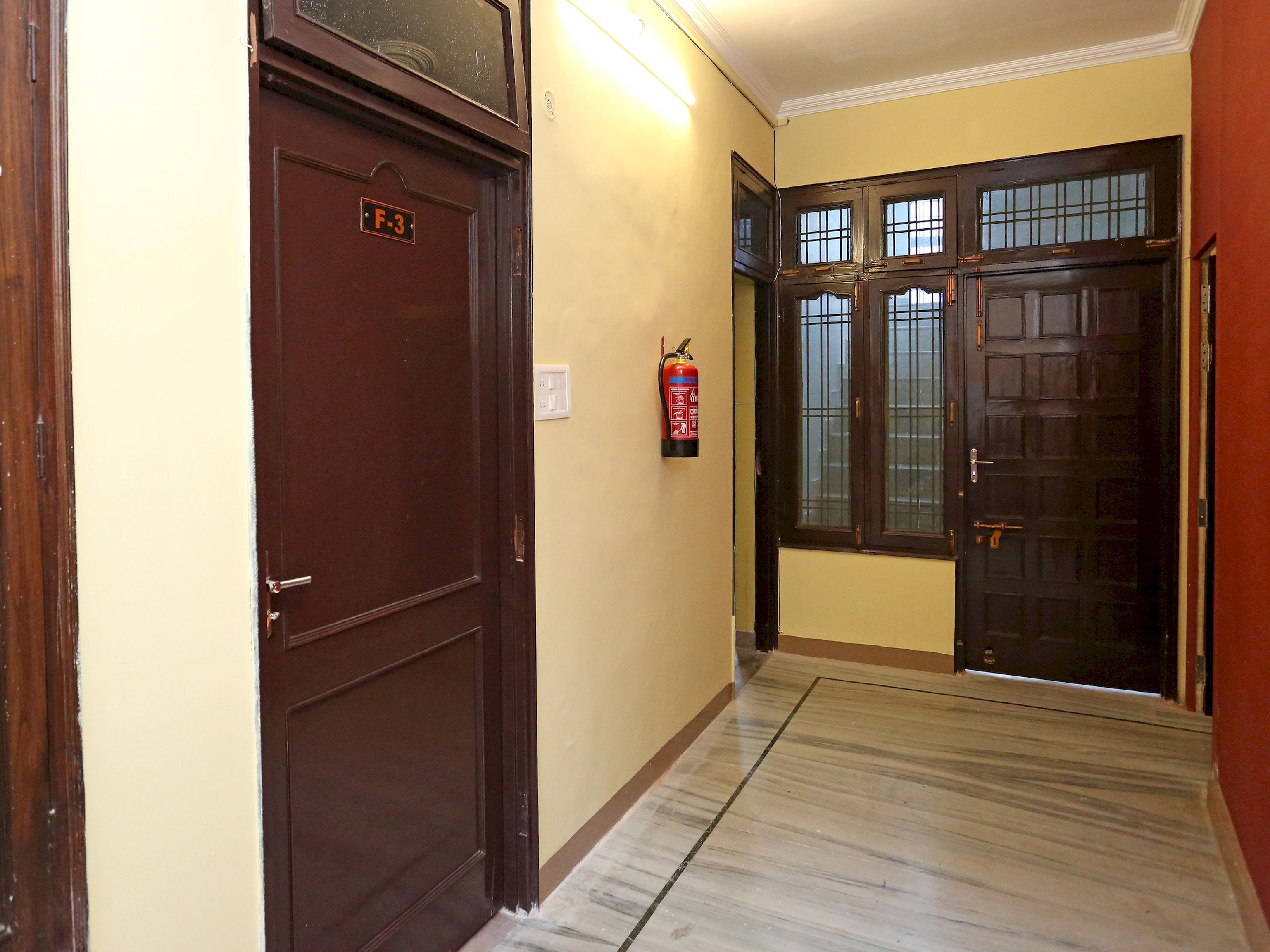 A hallway with a fire extinguisher mounted on the wall, a door labeled 'F-3', and a double door with glass panels.