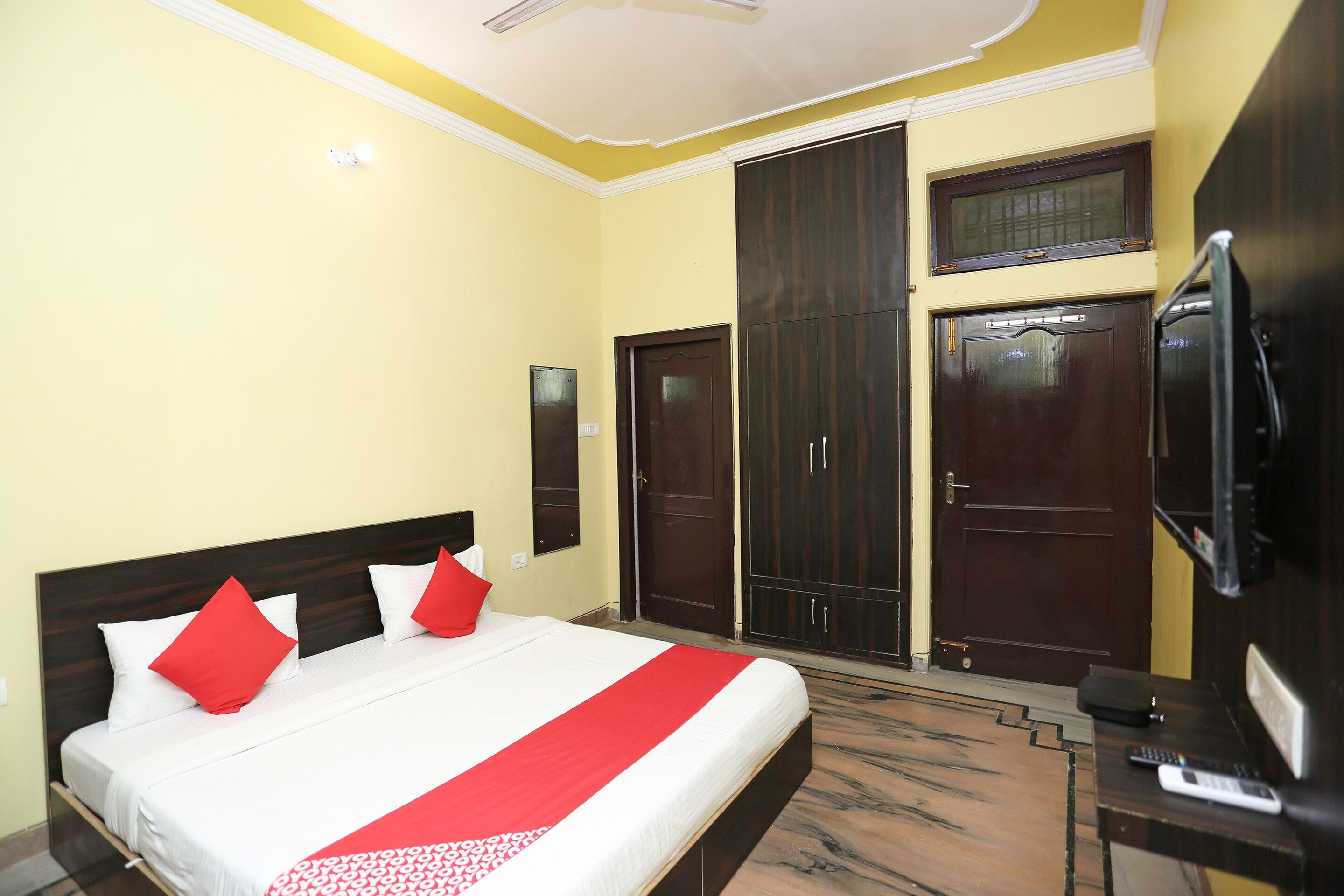 A hotel room with a bed, a wardrobe, a television, and a ceiling fan.