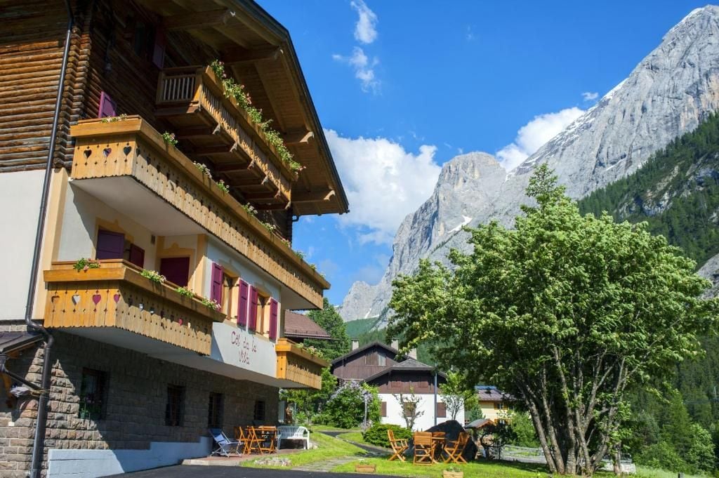 A traditional chalet with balconies, a mountain backdrop, and a clear sky.