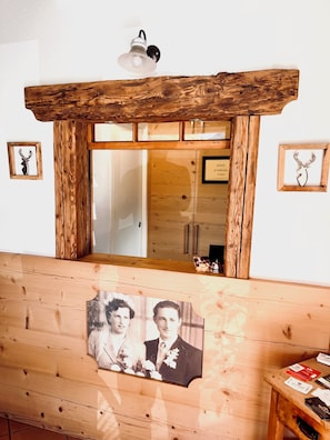 A wooden bench with a framed photograph, a wall-mounted light fixture, and framed deer silhouettes. - garni col da la vila (Canazei)