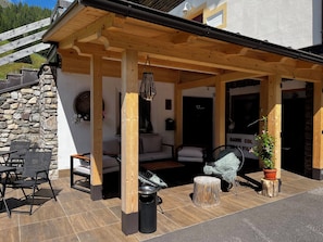 A covered outdoor seating area with stone walls, a wooden pergola, and a stone staircase. - garni col da la vila (Penia di Canazei)