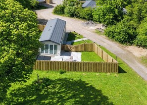 En bostadsfastighet med ett fristående hus, en inhägnad trädgård och en uppfart.