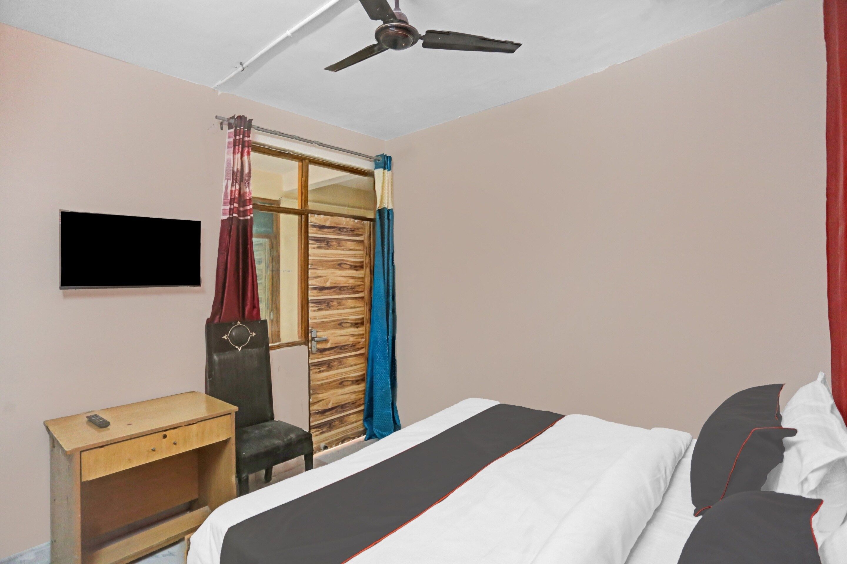Un dormitorio con cama, escritorio, silla, armario y ventilador de techo.