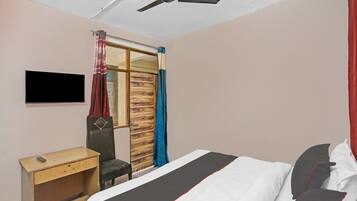 Un dormitorio con cama, escritorio, silla, armario y ventilador de techo.
