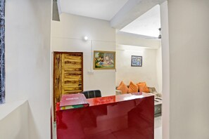 A hotel reception area with a wooden door, a painting on the wall, and a sofa with orange cushions. - Hotel O Golden (Noida)