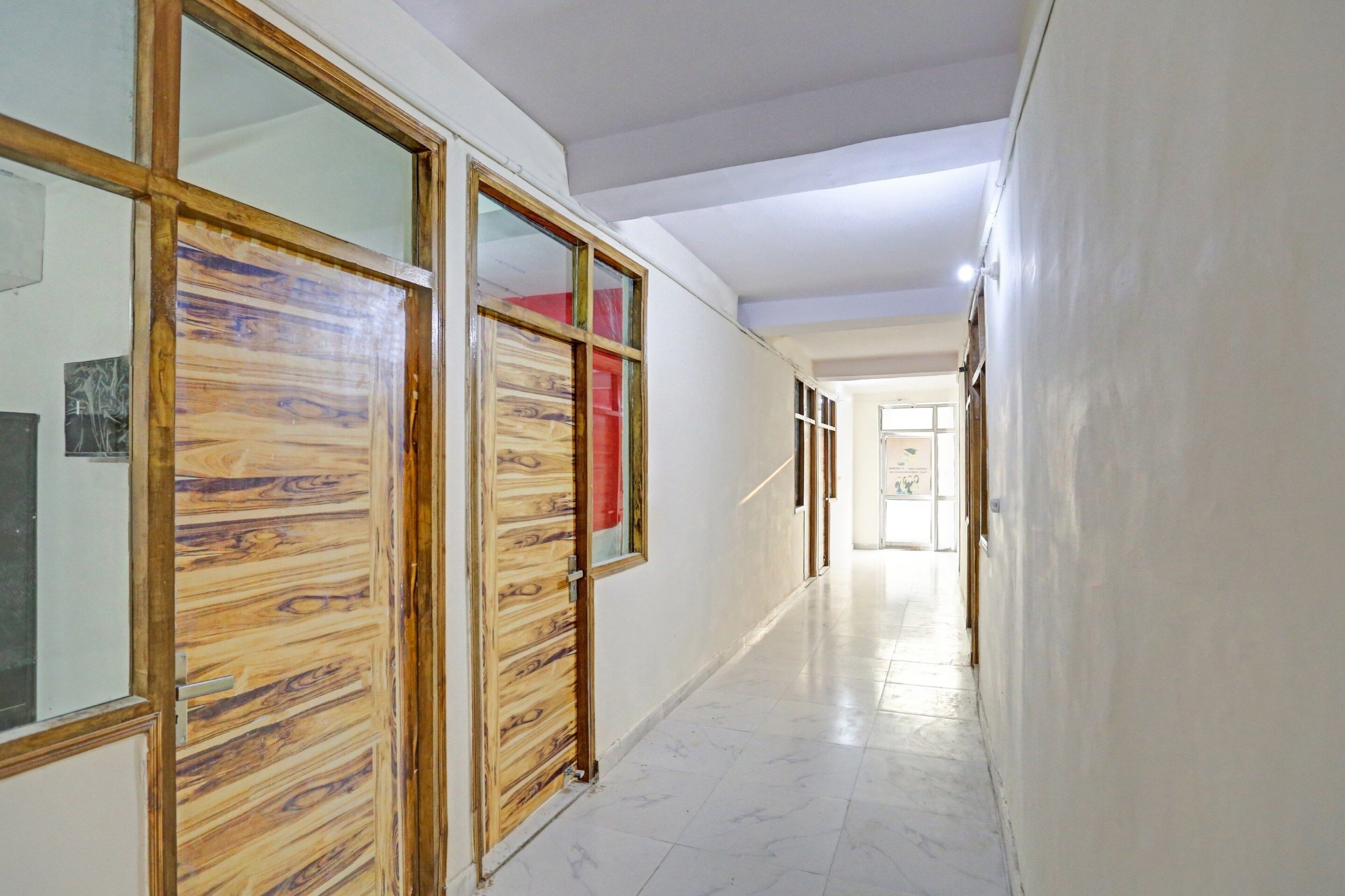 Un pasillo con puertas de madera y piso de baldosas.