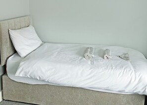A bed with a white sheet and two decorative pillows. - A beautifully restored two-storey, two bedroom cottage sleeping four people. (Filey)