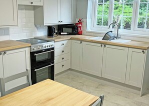 A kitchen with a stove, oven, microwave, and sink. - A beautifully restored two-storey, two bedroom cottage sleeping four people. (Filey)