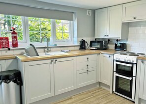A kitchen with white cabinets, a sink, a kettle, a microwave, and an oven. - A beautifully restored two-storey, two bedroom cottage sleeping four people. (Filey)