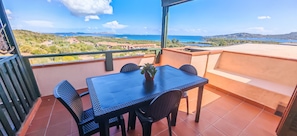A terrace with a table and chairs, a potted plant, and a view of the sea and landscape. - Casa Tanca Manna - View of Caprera & La Maddalena (Tanca Manna)