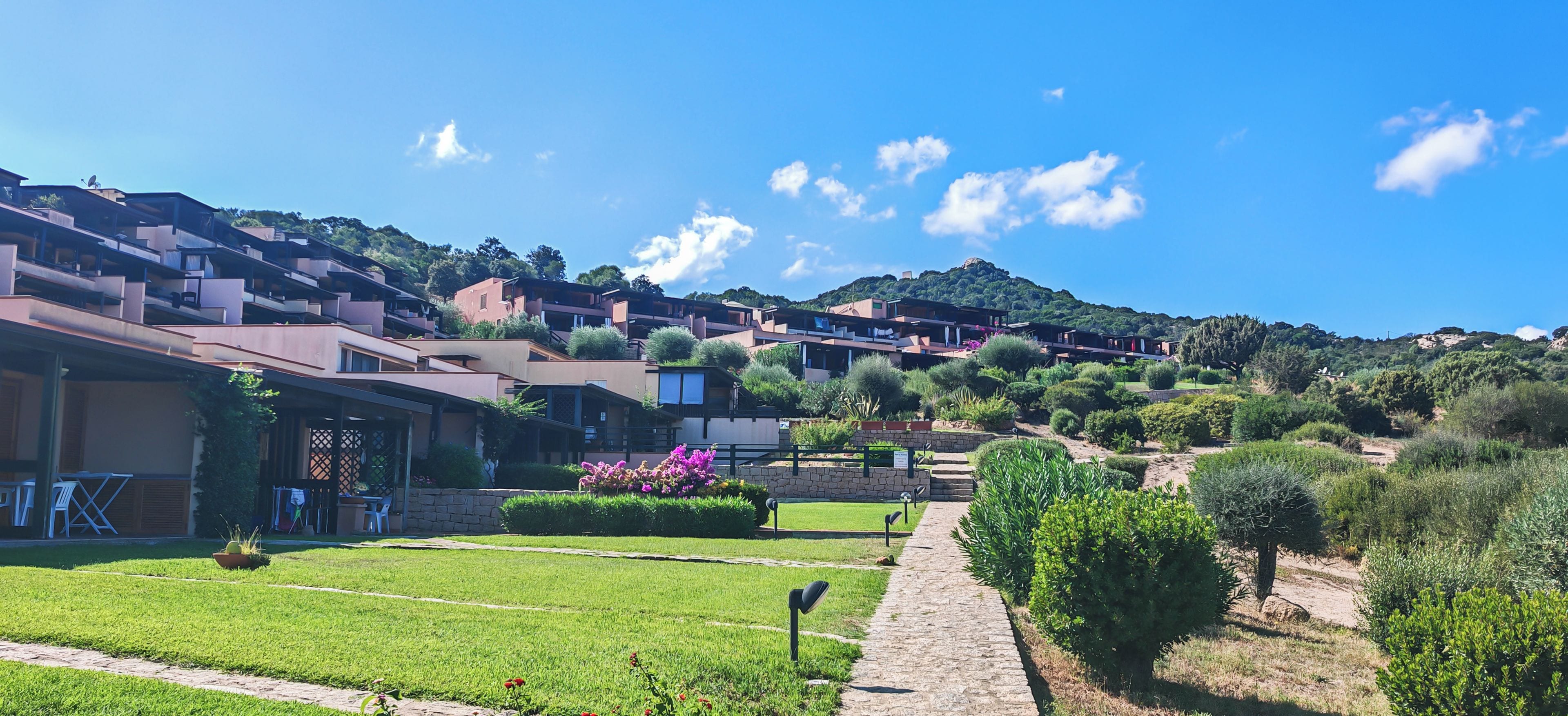 Zona residencial con casas modernas, un camino pavimentado y una colina con vegetación.
