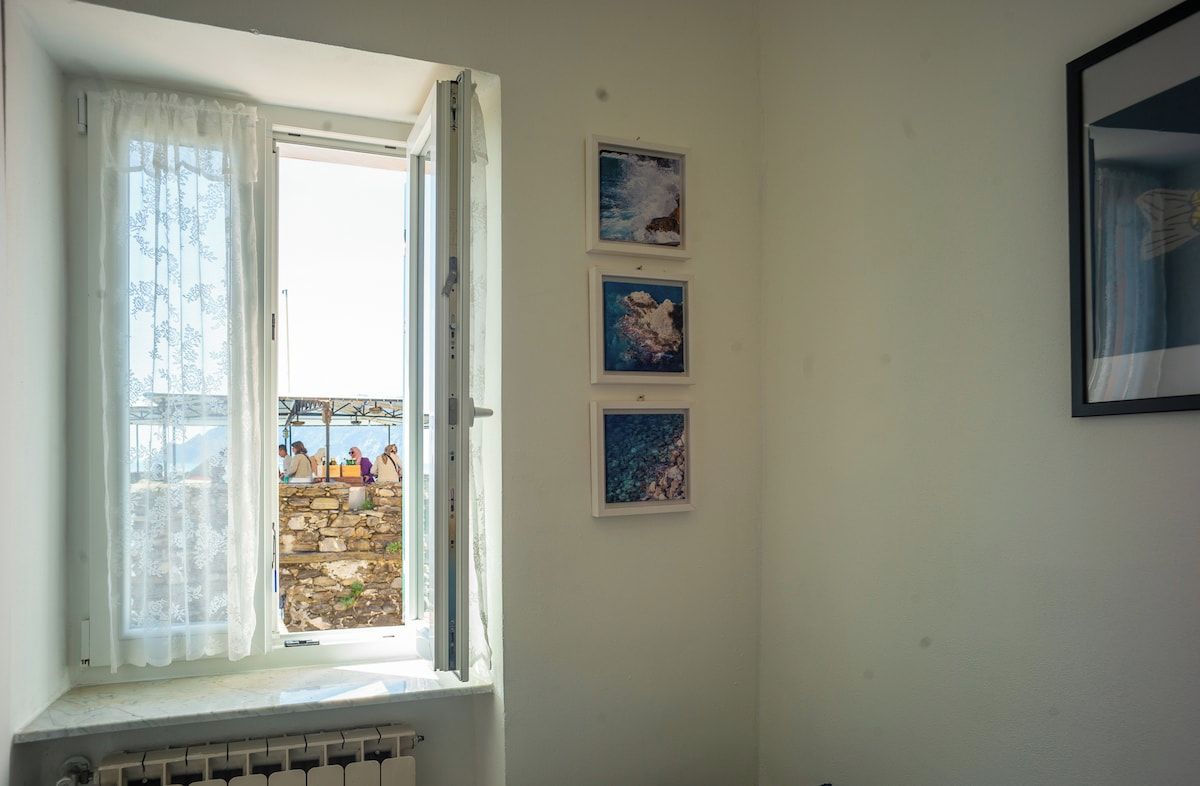 Ein Zimmer mit Fenster, Heizkörper und drei gerahmten Bildern an der Wand.