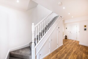A staircase with white balusters and a grey carpeted landing. - Stunning High-End 3 Bedroom Camden Flat (London)