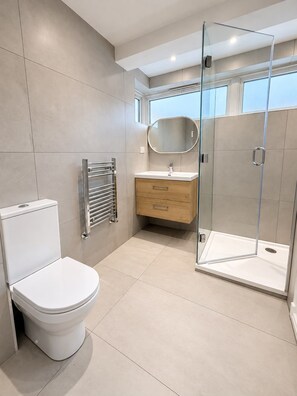 Un baño moderno con inodoro, tocador y ducha con mampara de vidrio.