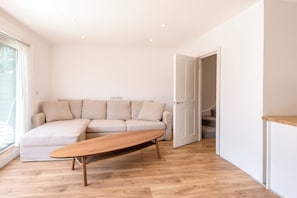 A modern living room with a sofa, a wooden coffee table, and a staircase leading to another level. - Stunning High-End 3 Bedroom Camden Flat (London)