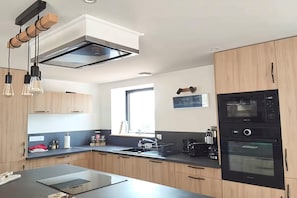 A modern kitchen with a central island, built-in appliances, and pendant lighting. - Serene Holiday Home with Pool in Souillac (MONTFAUCON)