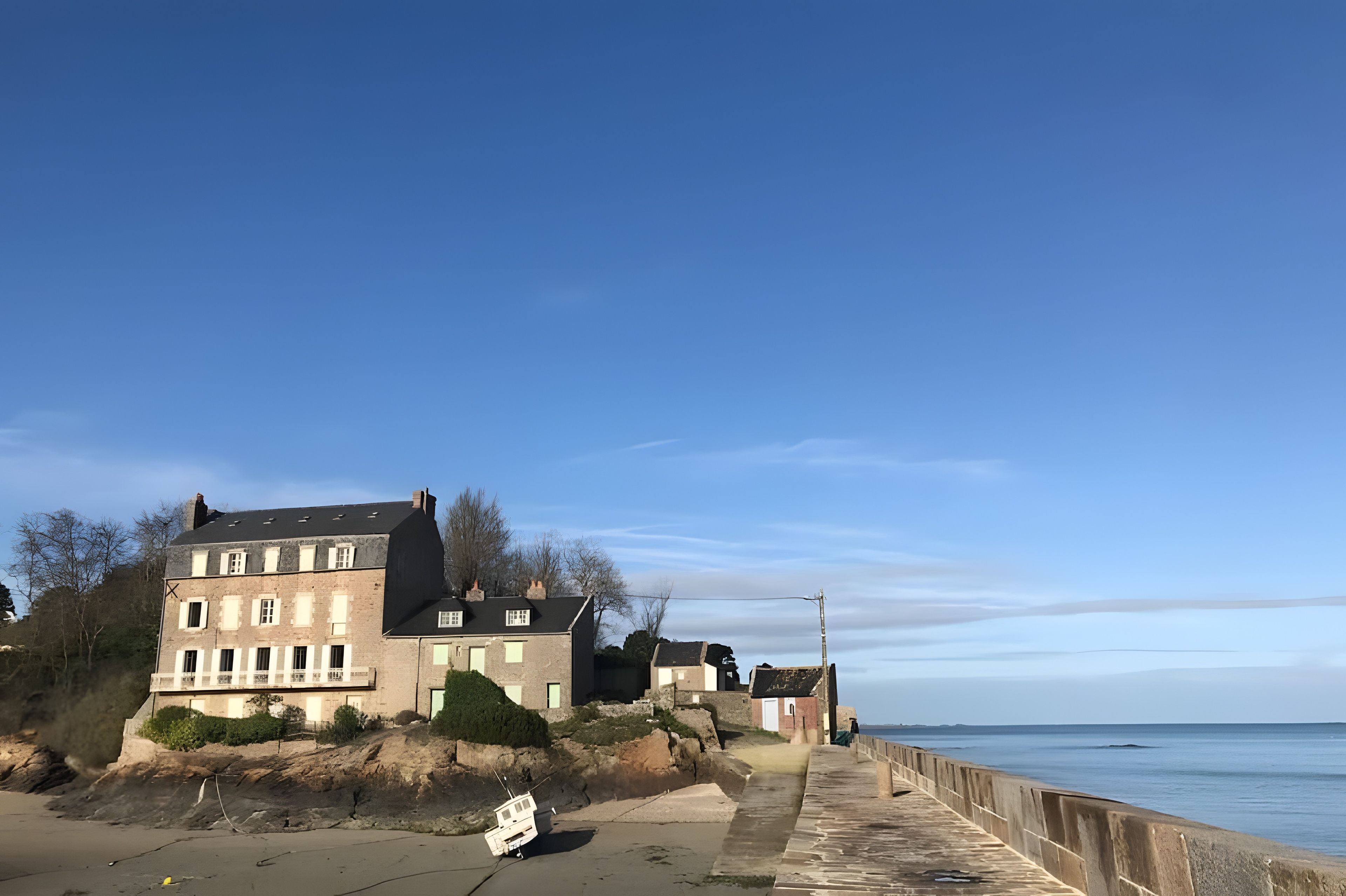 A coastal building with a paved walkway leading to the sea.
