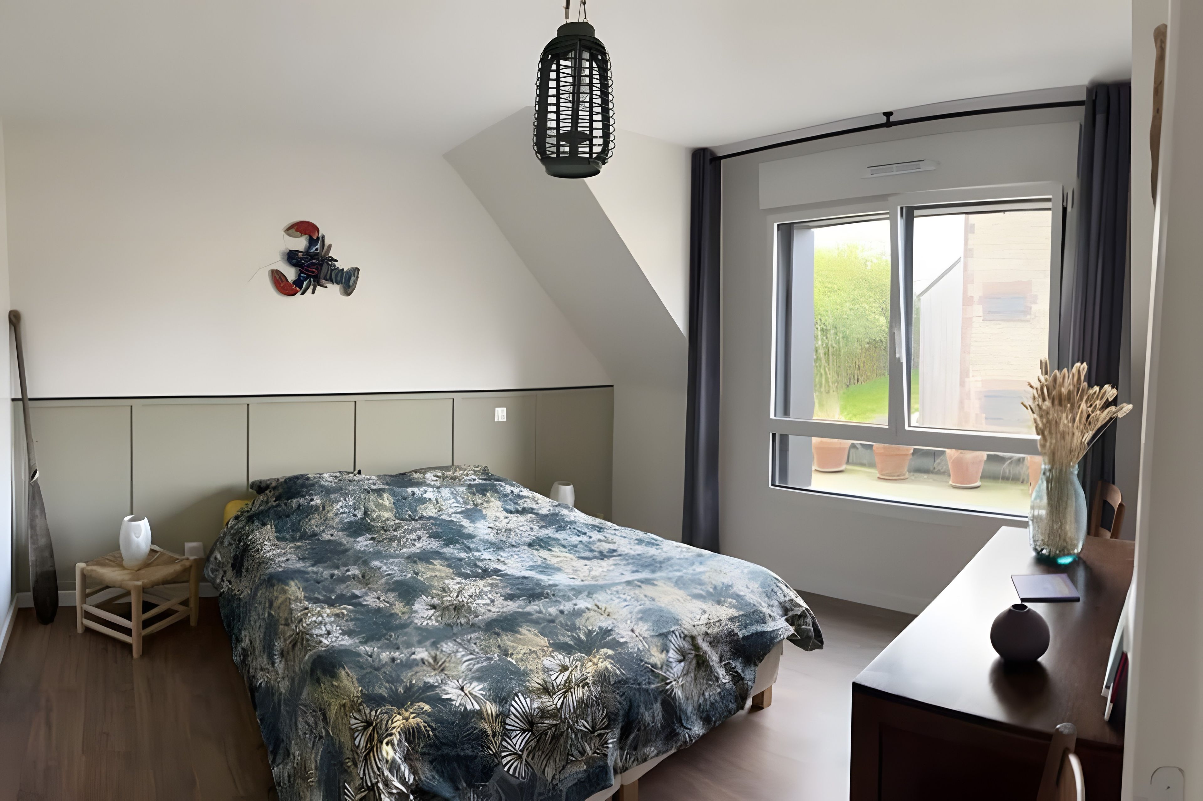 Een slaapkamer met een bed, een hanglamp, een raam met uitzicht en een tafeltje met een vaas.