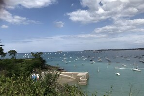 A coastal view with numerous boats, a clear sky, and a stone pier.