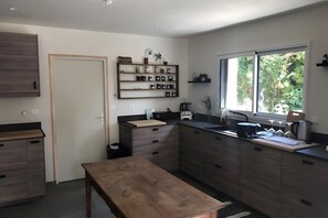 A modern kitchen with a wooden bench, built-in cabinets, and a window with a view of greenery.
