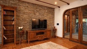 A living room with a stone wall, wooden entertainment unit, and a large flat-screen TV.