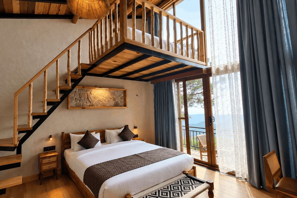 A bedroom with a wooden staircase, a bed with pillows, a nightstand, and a view through a large window.
