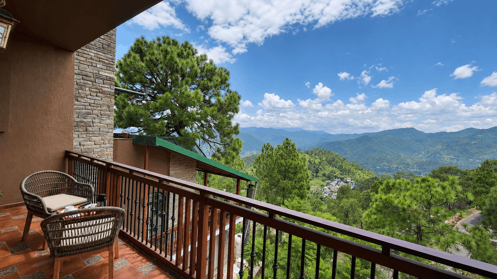 A balcony with wicker furniture and a view of a mountainous landscape.