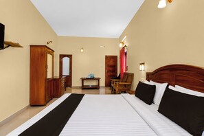 A hotel room with a large bed, wooden furniture, a desk, and a mirror. - Collection O Elephant Camp Thekkady (Thekkady)