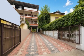 A gated pathway leading to a multi-story building with a sign indicating 'Collection' and 'ovo-serviced' services. - Collection O Elephant Camp Thekkady (Thekkady)