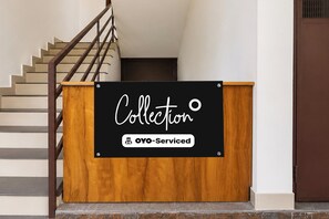 A wooden podium with a sign that reads 'Collection' and 'OYO-Serviced' against a staircase backdrop. - Collection O Elephant Camp Thekkady (Thekkady)