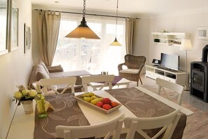 A dining area with a table set for four, a television, and a sofa. - Holiday apartment with 2 bedrooms (Burg auf Fehmarn)