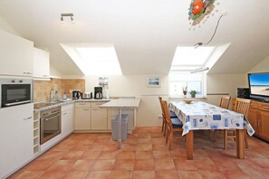 A kitchen with a dining area, equipped with a stove, oven, sink, and a table set for dining. - Noelia holiday apartment on the west beach 319643 (Kühlungsborn - West)