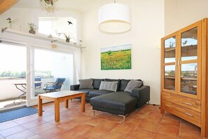 A living room with a sofa, a wooden cabinet, and a painting on the wall. - Noelia holiday apartment on the west beach 319643 (Kühlungsborn - West)