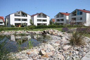 A residential area with modern apartment buildings, a small pond, and a landscaped garden. - Noelia holiday apartment on the west beach 319643 (Kühlungsborn - West)
