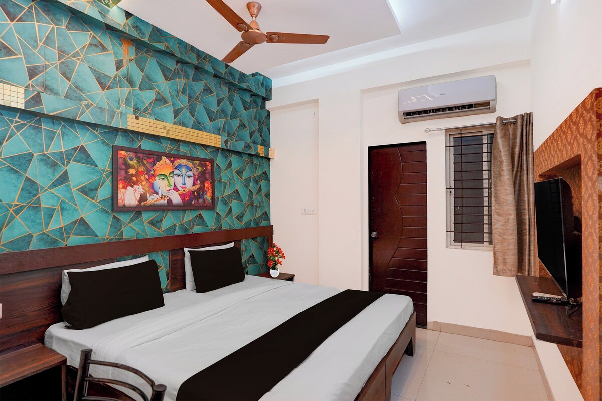A bedroom with a bed, a ceiling fan, a wall-mounted air conditioner, a door, and a television.